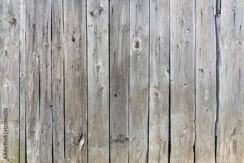 Alte, graue, verwitterte Holzwand aus vertikalen Brettern