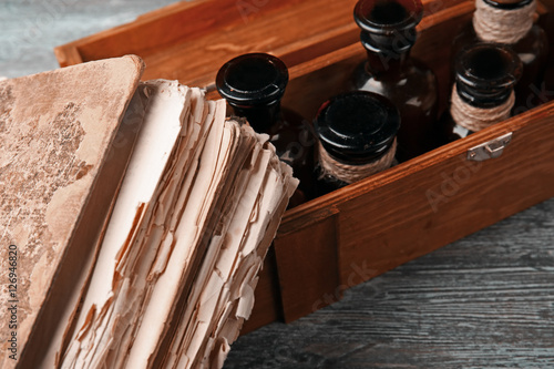Vintage glass bottles in wooden box with old book, closeup
