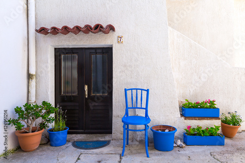 Traditional European Mediterranean architectural style in the streets and residential houses, porches, stairs, shutters in the noon sunbeam, surrounded by vine, hydrangea and palm at summertime. Baska