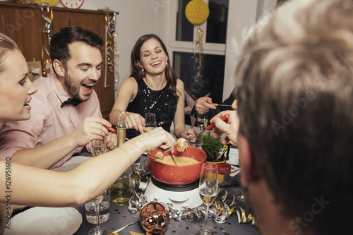Friends eating cheese fondue on New Year's Eve photo