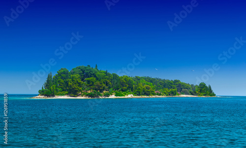 a small green island in the calm sea in warm summer day