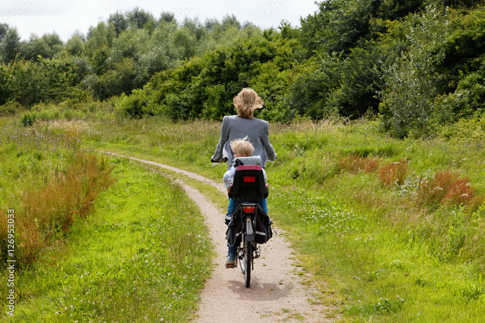 Blond boy on the back of a bicicle cycling away