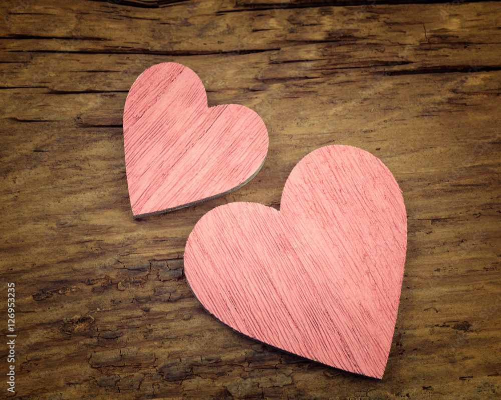 Two pink wooden hearts placed nicely on a rustic vintage wood Two pink wooden hearts placed nicely on a rustic vintage wood
