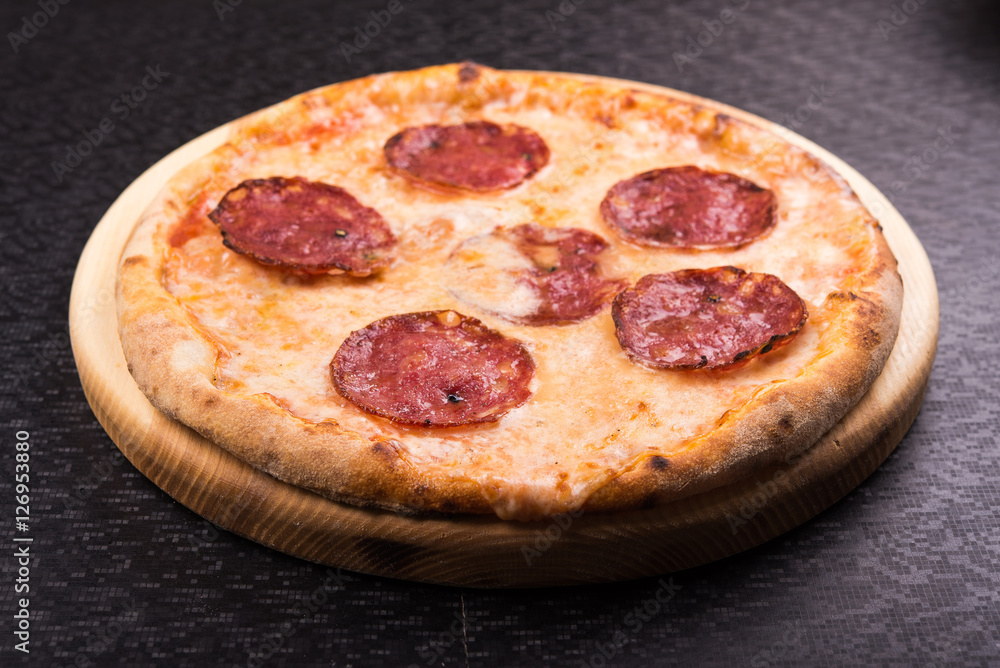 hot pepperoni pizza on wooden board
