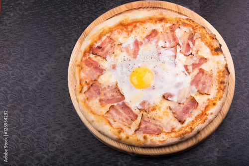 pizza carbonara with bacon and raw hicken egg photo