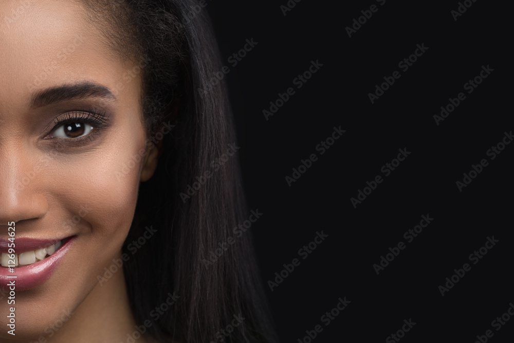 Half-face portrait of beautiful smiling sensitive afro american woman on dark background Half-face portrait of beautiful smiling sensitive afro american woman on dark background