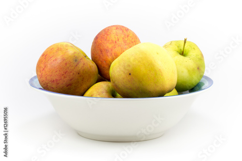 Colorful windfall apples in a bowl on a white background.