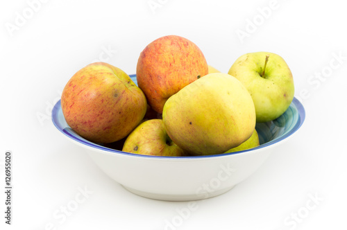Windfall apples grouped in a bowl on a white background.