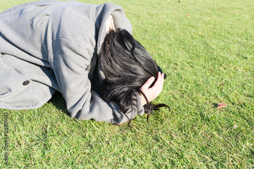 芝生の上に崩れ落ちる女性