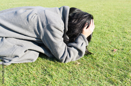 芝生の上に崩れ落ちる女性