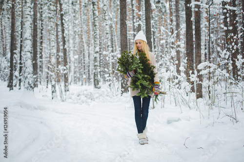 girl in winter forest holds branches in his hands