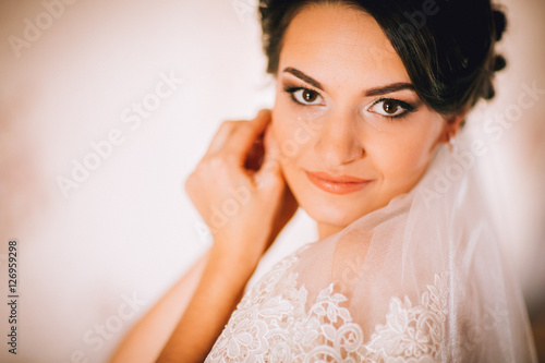 Amazing glance of the bride with the veil in the morning preparation. Wear jewelry