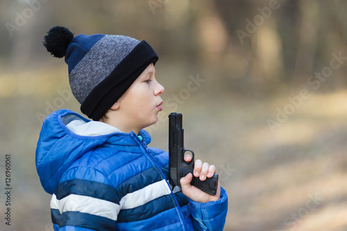 boy playing with a toy gun on the street in autumn photo