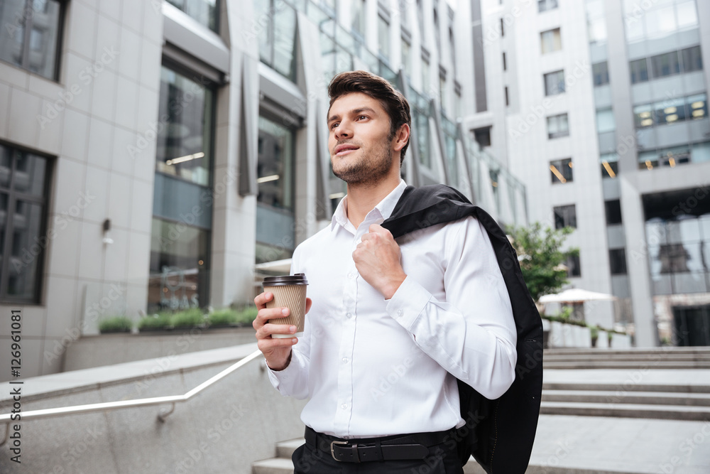Businessman with jacket and coffee walking near business center Businessman with jacket and coffee walking near business center