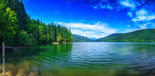 Panoramic view of beautiful lake and spruce forest in mountains at sunshine © Sodel Vladyslav