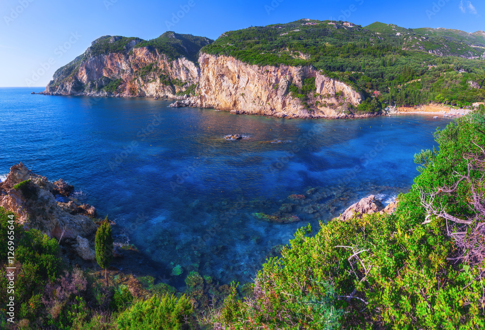 Landscape of Paleokastritsa famous beach in close bay with crystal clear azure water on Corfu island, Ionian archipelago, Greece.