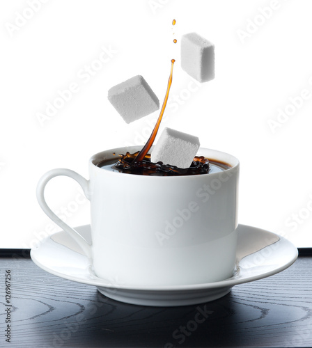Cup of coffee with falling sugar cube isolated on white backgro