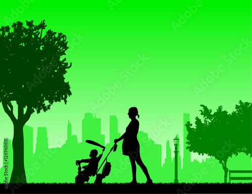 Pregnant woman walking with baby on a tricycle in park, one in the series of similar images silhouette