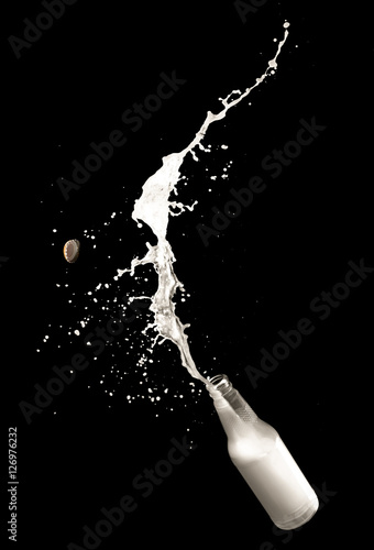 Milk bottle and splashes isolated on black background