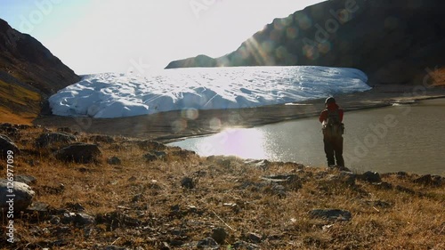 A hiker stops to photograph a glacier in Etha, Greenland photo