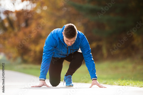 Young runner in park on asphalt path in steady position