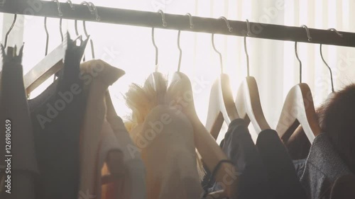 Close-up: a hanger for clothing. Designer clothing collection. Designer with a ready collection. Sunlight between hangers for clothes. Solar Design Studio. Atelier, bathed in natural sunlight.