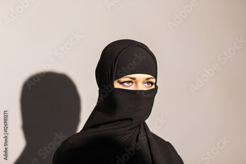 Young woman wearing niqab on background