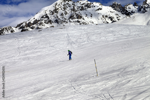 Skier on ski slope at sun winter day