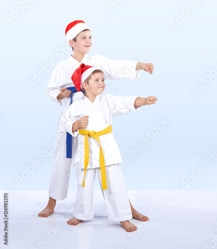 The boys in caps of Santa Claus beat punch arm