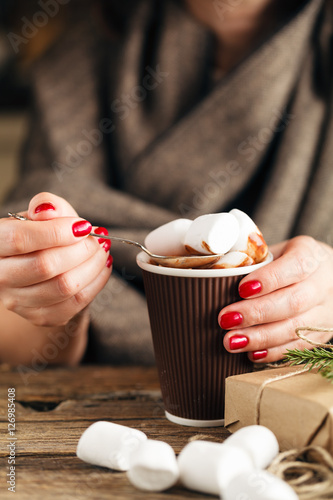 female hand holding cup of hot cocoa or chocolate with marshmall photo