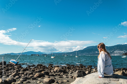 Girl Sitting on a Rock at Kitsilano Beach in Vancouver, Canada