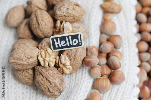 Walnuts. Hello. Healthy morning. Walnuts on white knitted background. Hello chalkboard