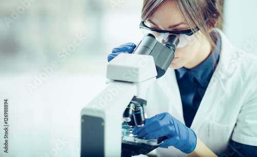 Photo Young scientist looking through a microscope in a laboratory