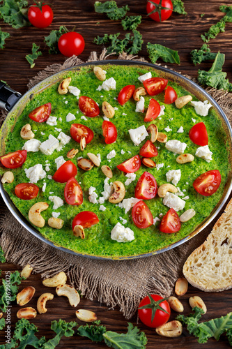 Vegetables Green Omelette with tomatoes, kale, greek cheese, olives, nuts, toast on wooden background. concept healthy food © grinchh