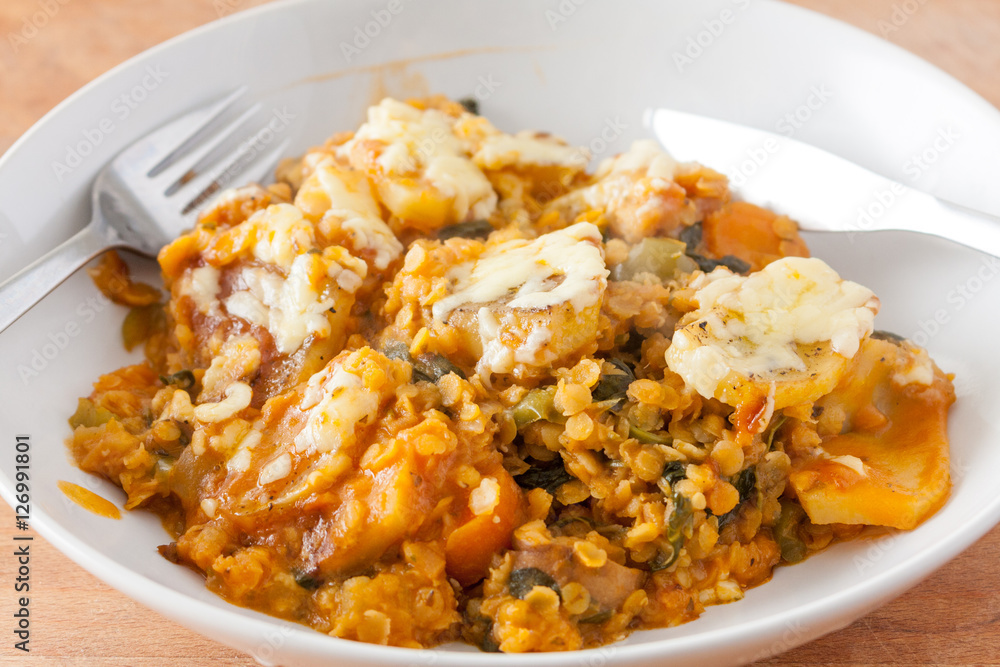 Lentil and vegetable hotpot with a cheesy potato topping in a white china bowl