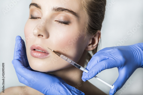 Slika na platnu Doctor aesthetician makes lips correction and augmentation to female patient