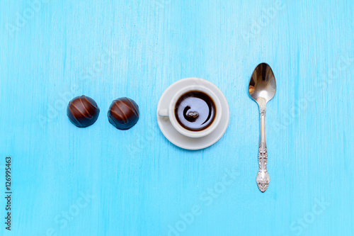 Миниатюрная чашка с кофе и двумя конфетами на столе