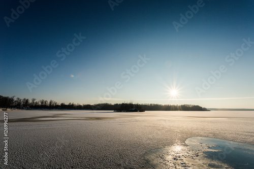 frozen lake on sunny winter's day with blue sky