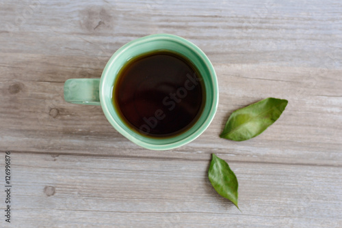 cup or mug of black tea with green leaves