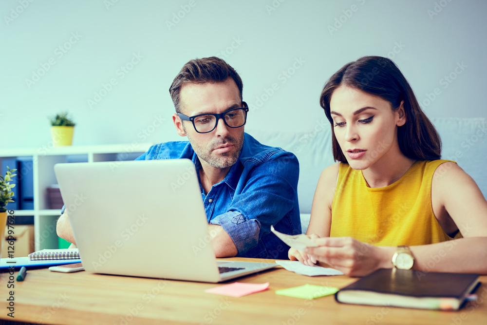 Worried couple paying bills online at home with laptop Worried couple paying bills online at home with laptop