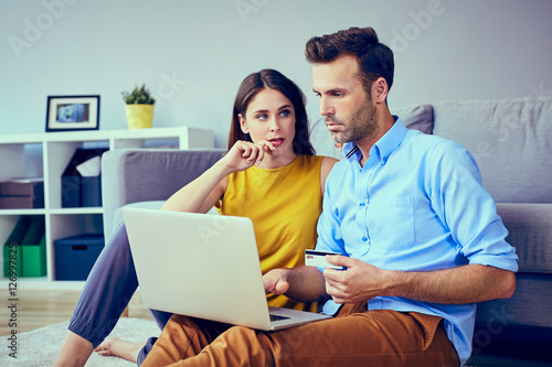 Sad couple doing online payments  on their laptop at home © baranq