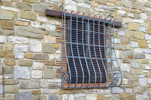 window with iron grating on stone wall
