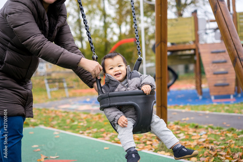 Baby and mother paly swing in the park