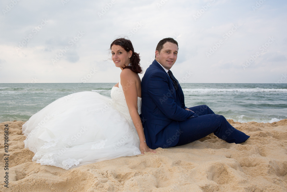 Couple on the beach in wedding dress back to back Couple on the beach in wedding dress back to back