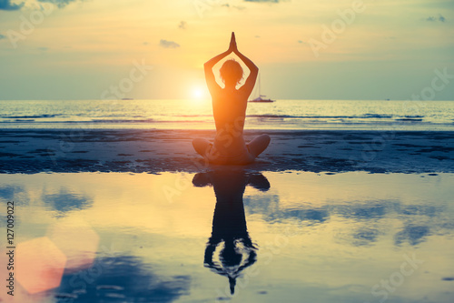 Silhouette woman yoga on the sea beach at sunset.