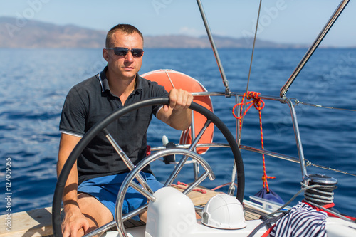 Man skipper steers boat sailing yacht on the Sea.