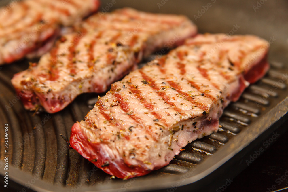Slices of beef strip loin stir-fried in a skillet-grill, visible