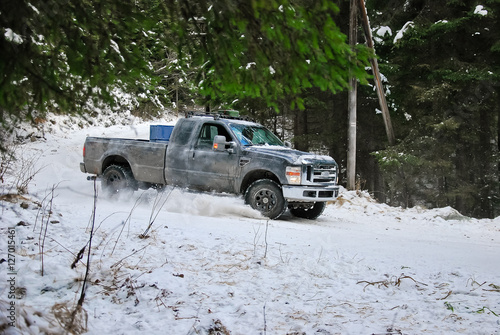Pickup truck rides winter snow road in a pine forest
