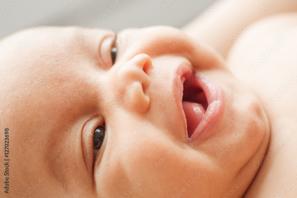 Face of laughing newborn child. Portrait of happy glad baby, widely smiling at his mom. Childhood, innocence, infant, happiness, family concept Face of laughing newborn child. Portrait of happy glad baby, widely smiling at his mom. Childhood, innocence, infant, happiness, family concept