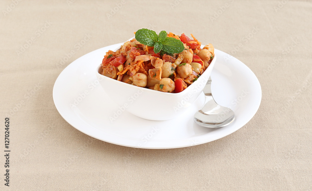 Indian vegetarian food channa chat, also known as chickpea or garbanzo curry, is eaten as a snack or is used as a side dish, in a bowl on a plate with a spoon. Indian vegetarian food channa chat, also known as chickpea or garbanzo curry, is eaten as a snack or is used as a side dish, in a bowl on a plate with a spoon.